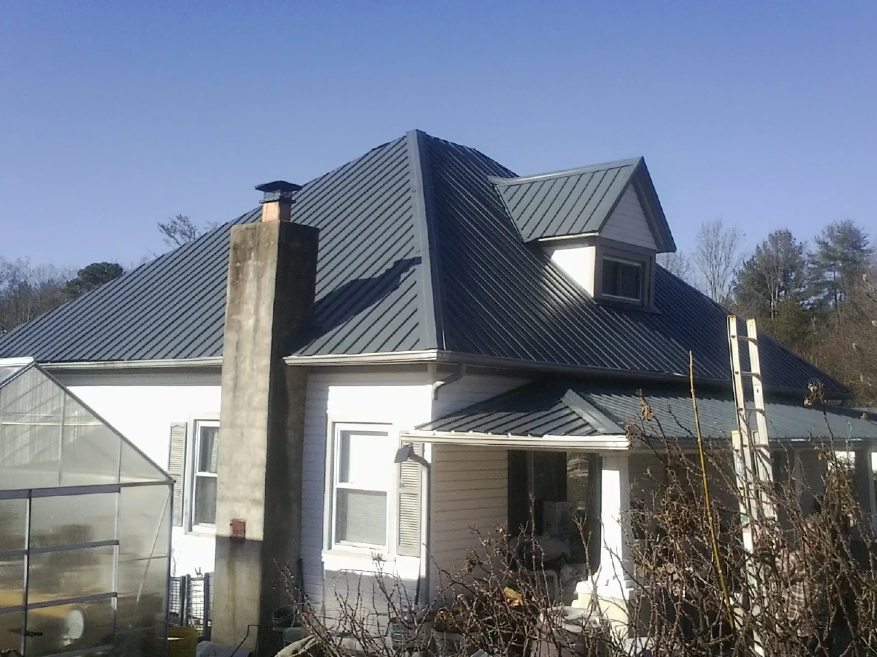Dark blue standing seam metal roof on a white farmhouse with dormer — Slate & Tile Roof Repair by Roofing Brothers in Larue