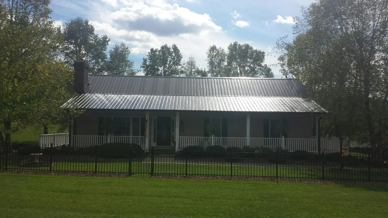 Gray metal roof on a brick ranch with a full width front porch — Gutter Guard Installation work by our crew in Larue